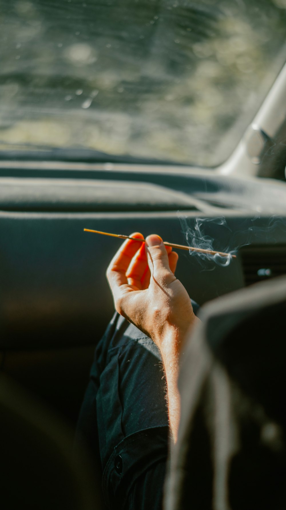 person holding cigarette stick in car