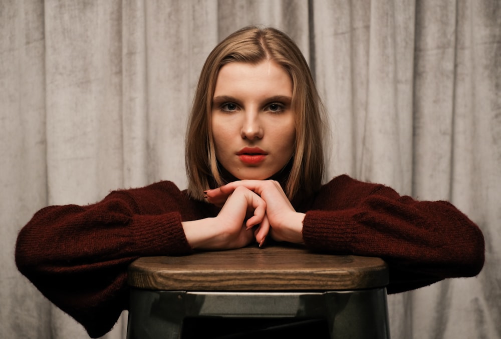 woman in red sweater leaning on black table