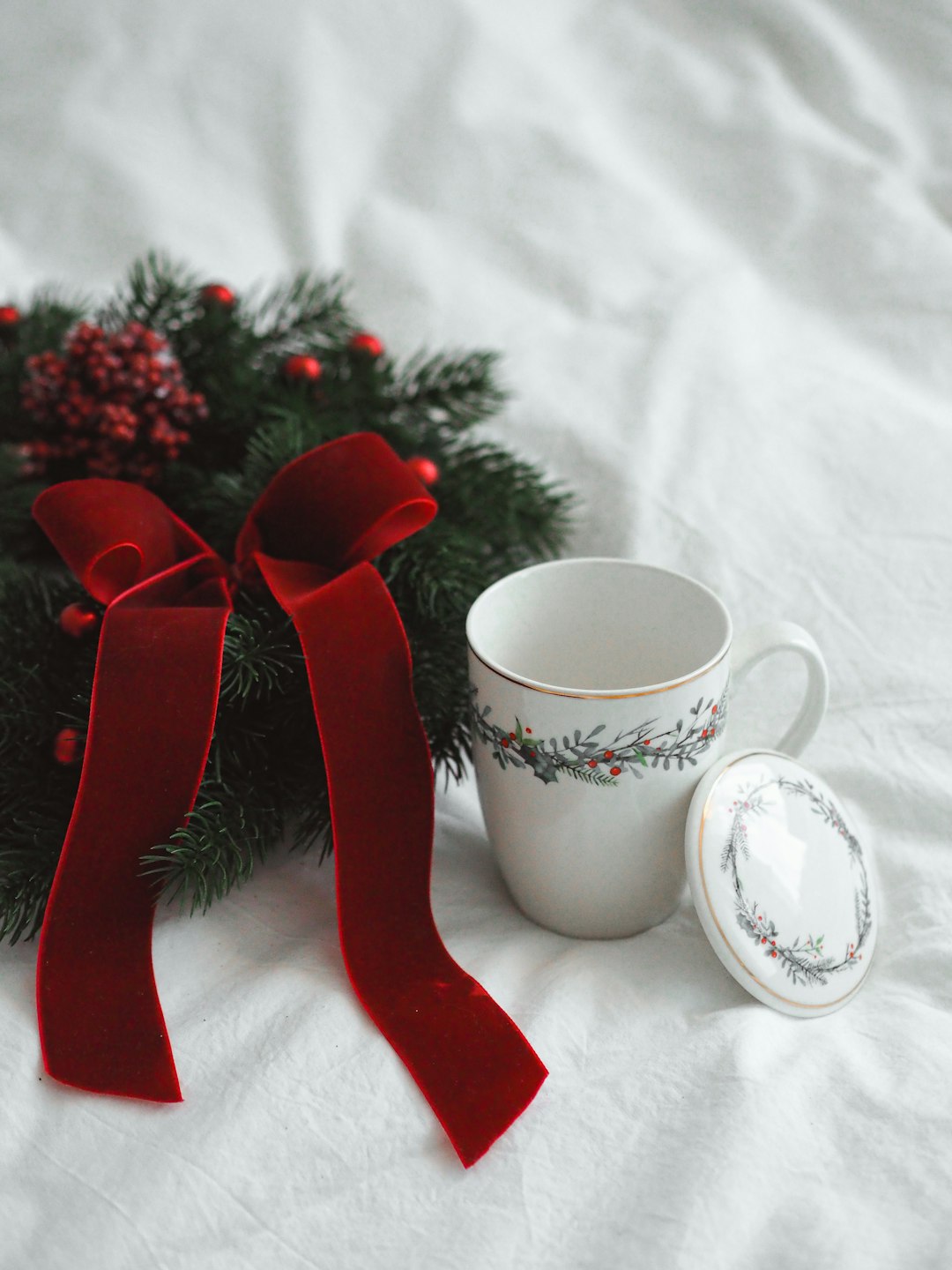 red and white ceramic mug with red ribbon on white textile