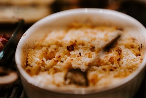 Close-up of a golden, buttery biscuit casserole bubbling with melted cheddar cheese and savory sausage pieces.