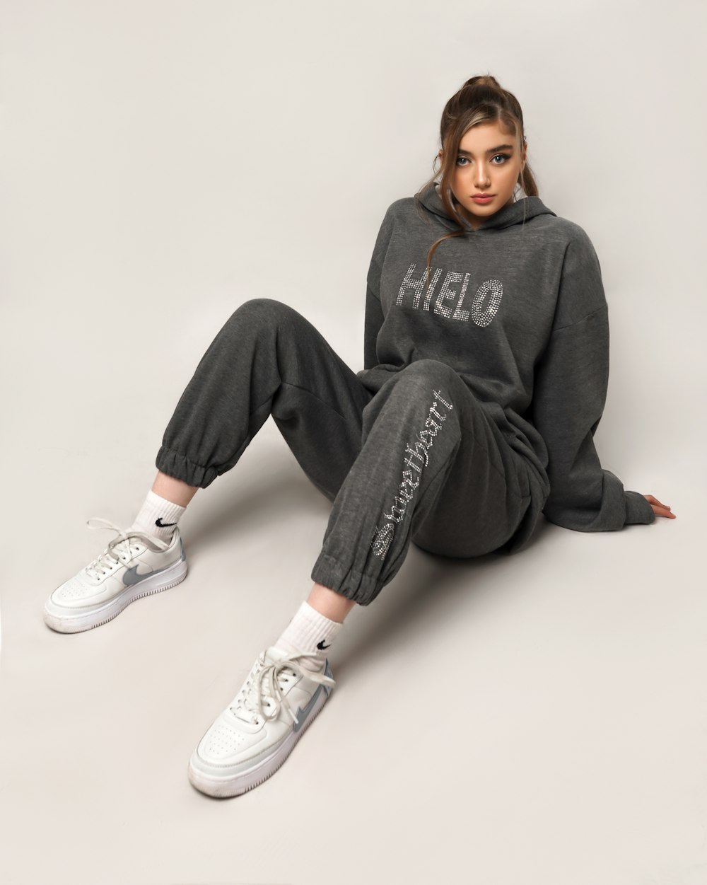 woman in gray hoodie and black pants sitting on white floor