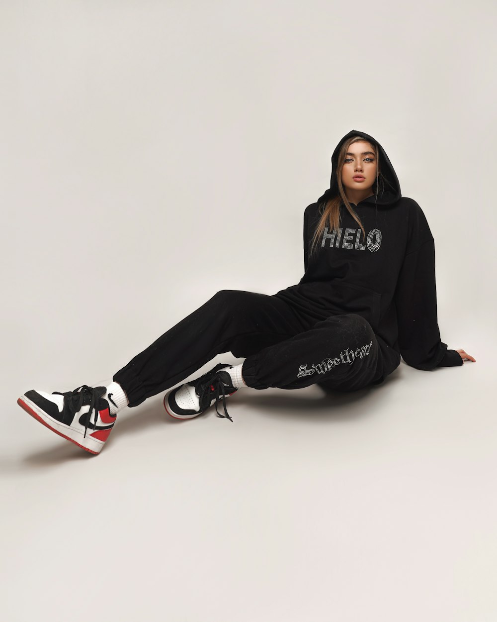 woman in black hoodie and black pants sitting on white floor