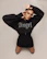 Model in a dramatic black gradient jacket with angelic and demonic symbols glowing faintly.