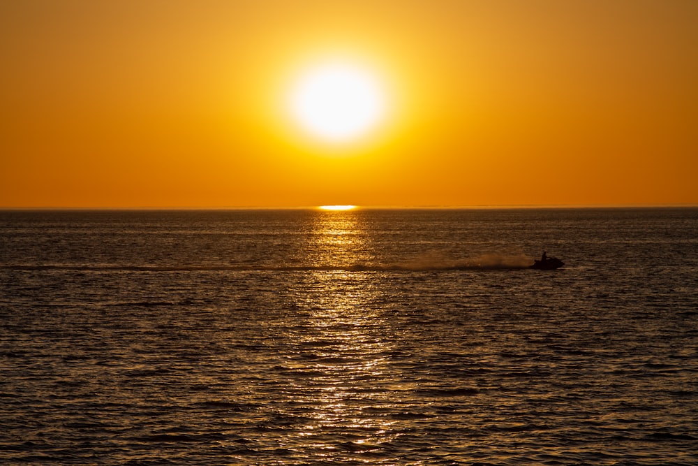 silhouette of person on sea during sunset