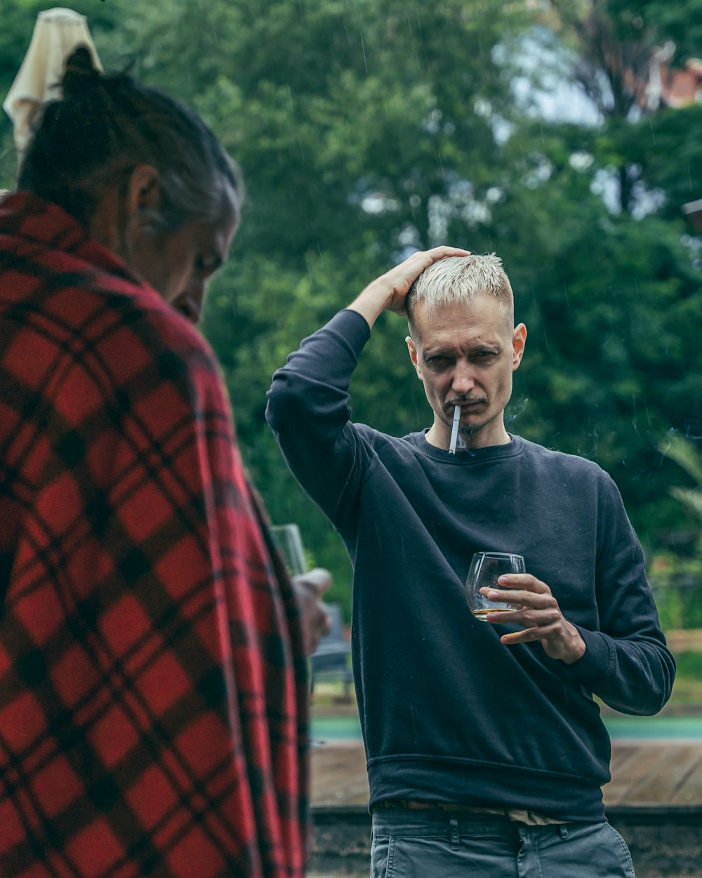 man in blue sweater smoking cigarette