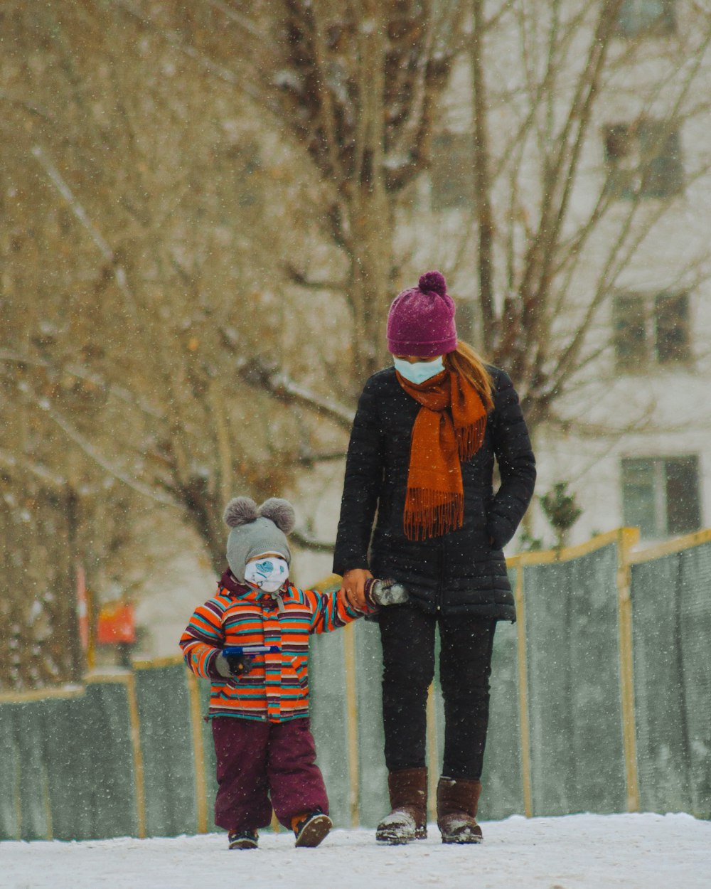 woman in black jacket and pink knit cap standing on snow covered ground during daytime