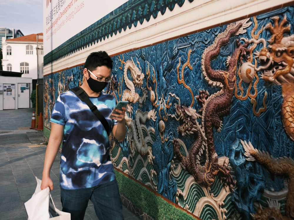 homem em camisa polo listra azul e branca de pé perto da parede com grafite