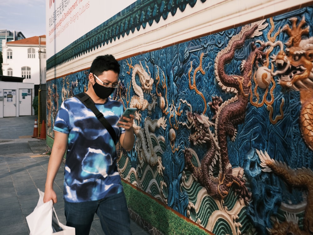 man in blue and white stripe polo shirt standing near wall with graffiti