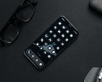 black remote control beside black framed eyeglasses