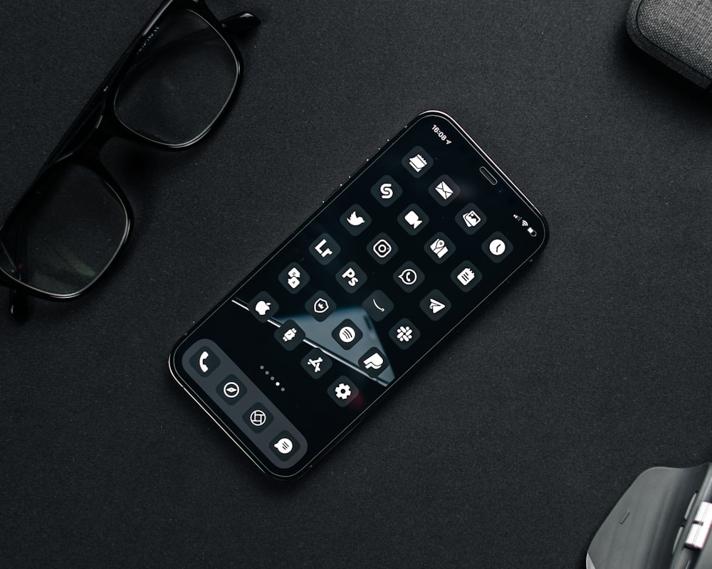 black remote control beside black framed eyeglasses