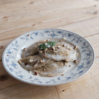 Artistic overhead shot of a rustic wooden table with assorted ravioli varieties and dipping sauces.