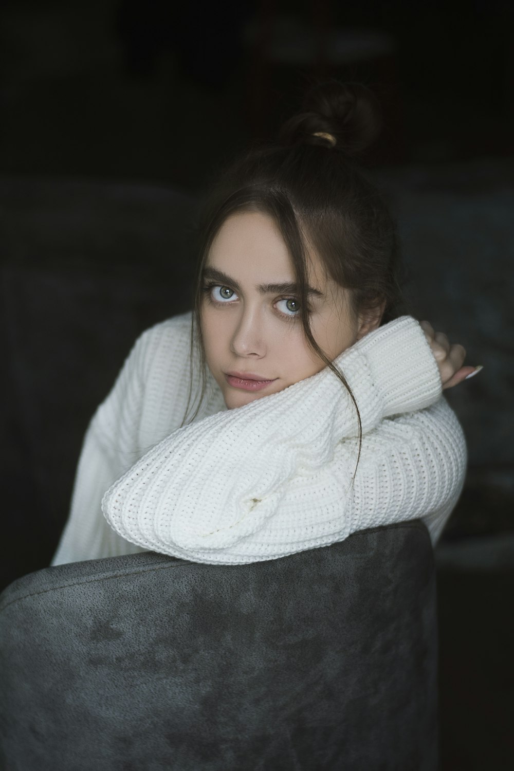 woman in white sweater lying on black textile