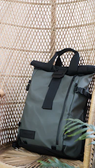 A stylish backpack hanging on a rustic wooden hook with natural light highlighting its modern design.