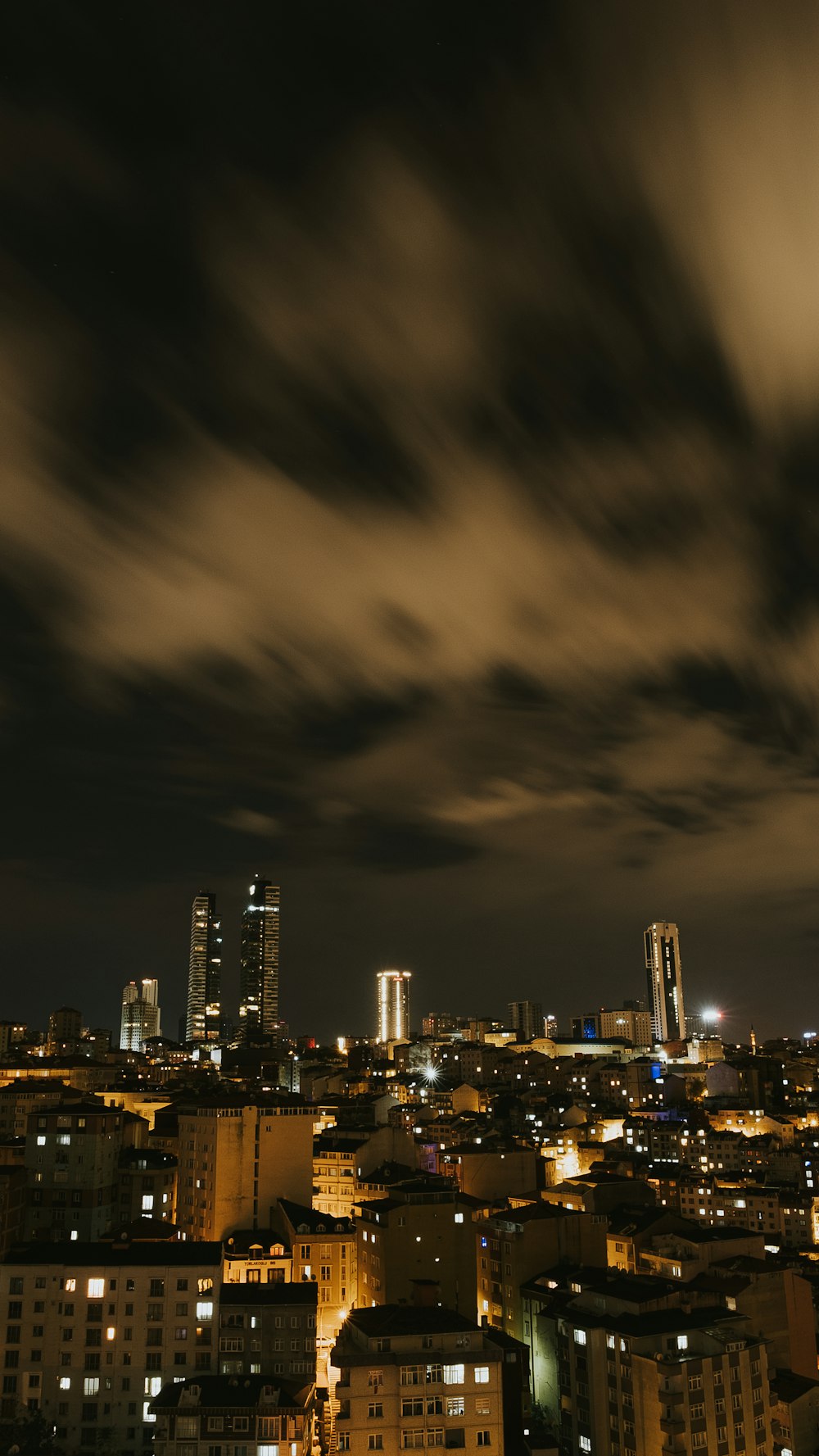 city skyline under gray clouds during night time