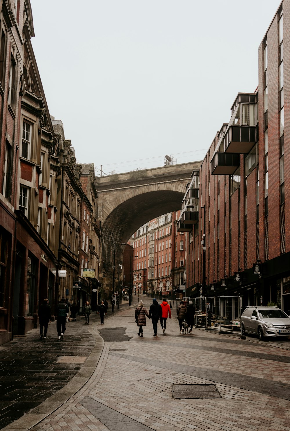 people walking on street between brown concrete buildings during daytime