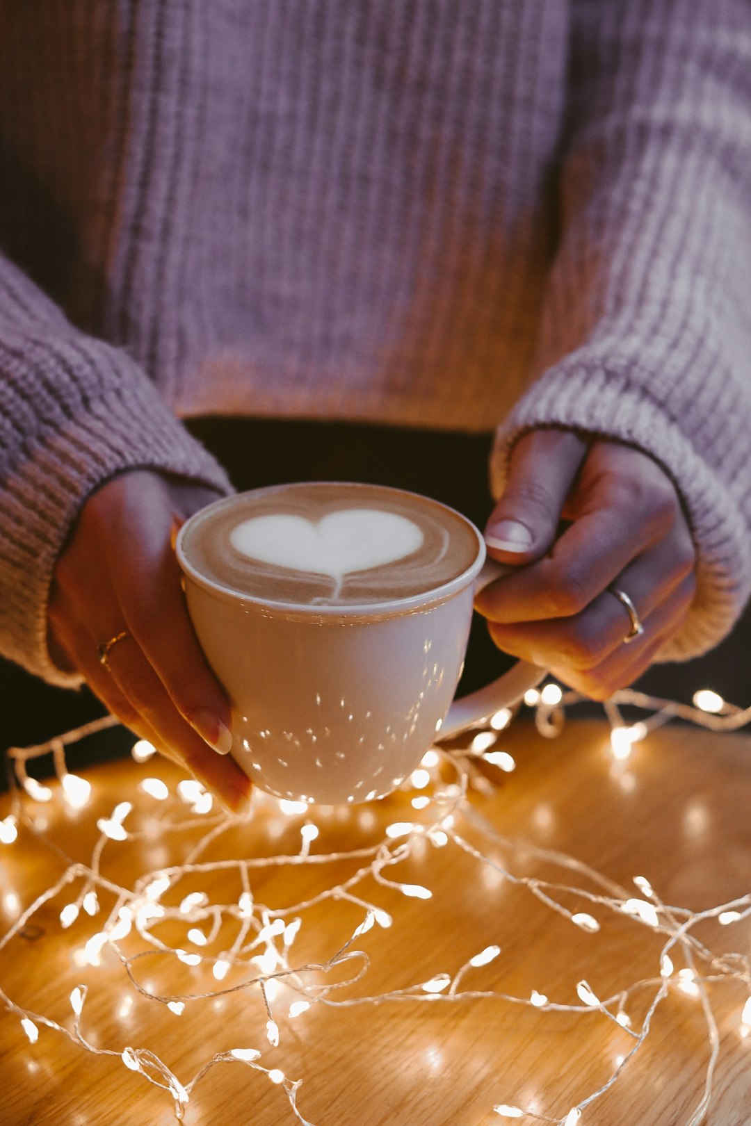 person in gray sweater holding white ceramic mug with coffee