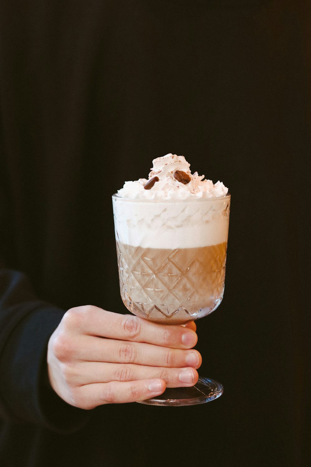 person holding ice cream in clear glass cup