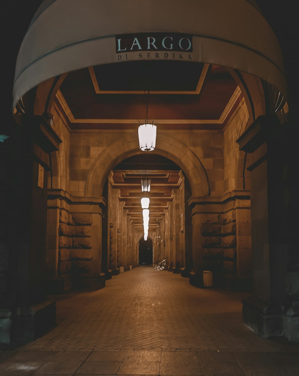 brown brick hallway with lights turned on during daytime