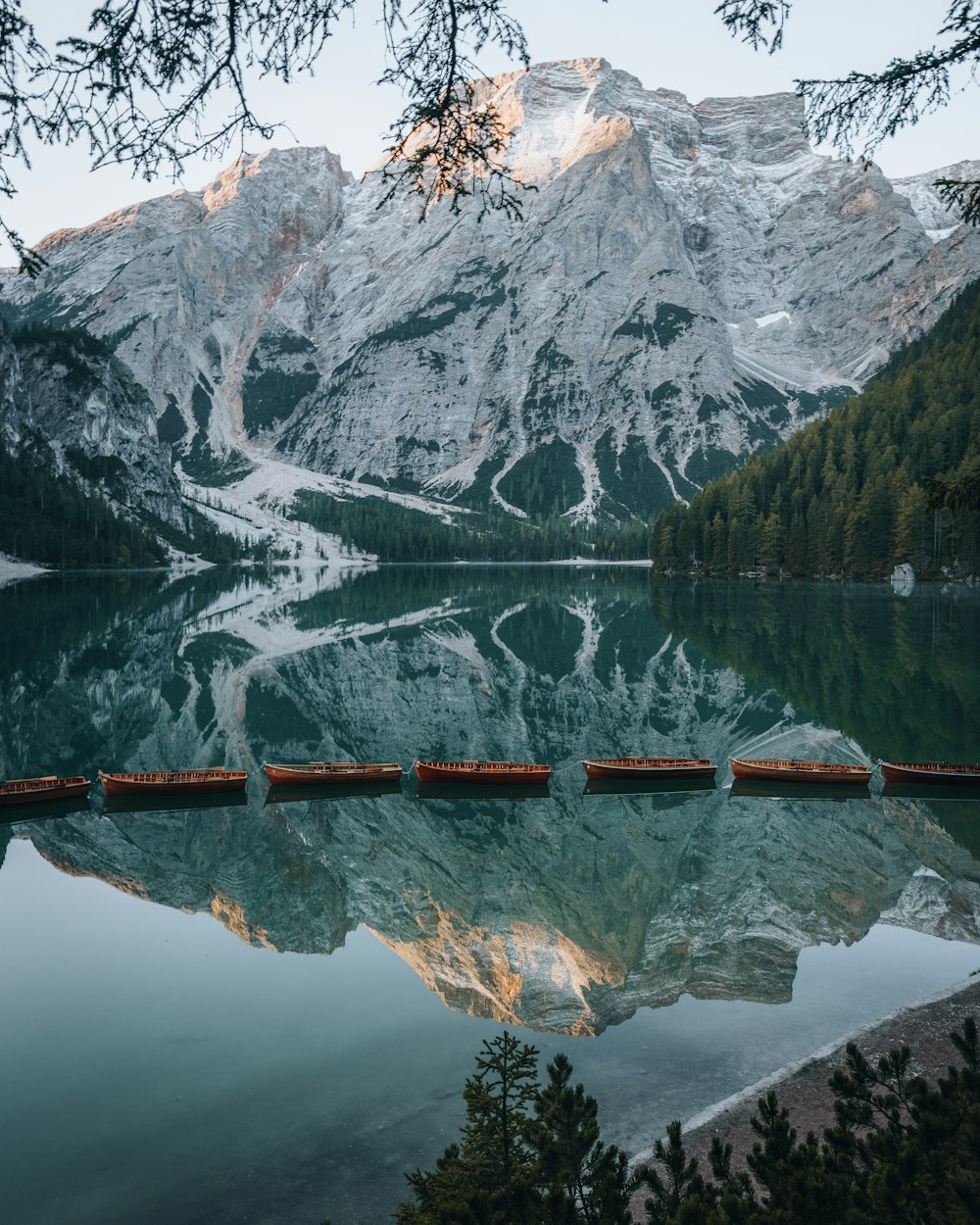 Pontile di legno marrone sul lago vicino alla montagna coperta di neve