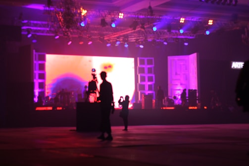 man in black suit standing on stage