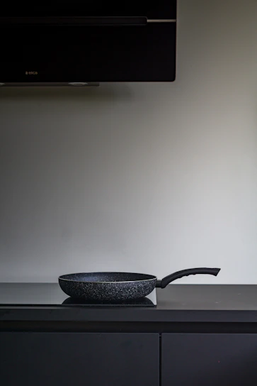 Close-up of a black granite non-stick wok pan on a wooden kitchen countertop