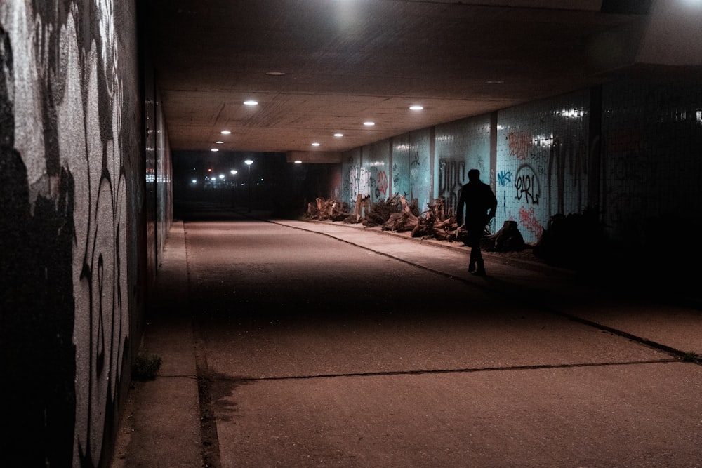 man in black jacket walking on street during nighttime