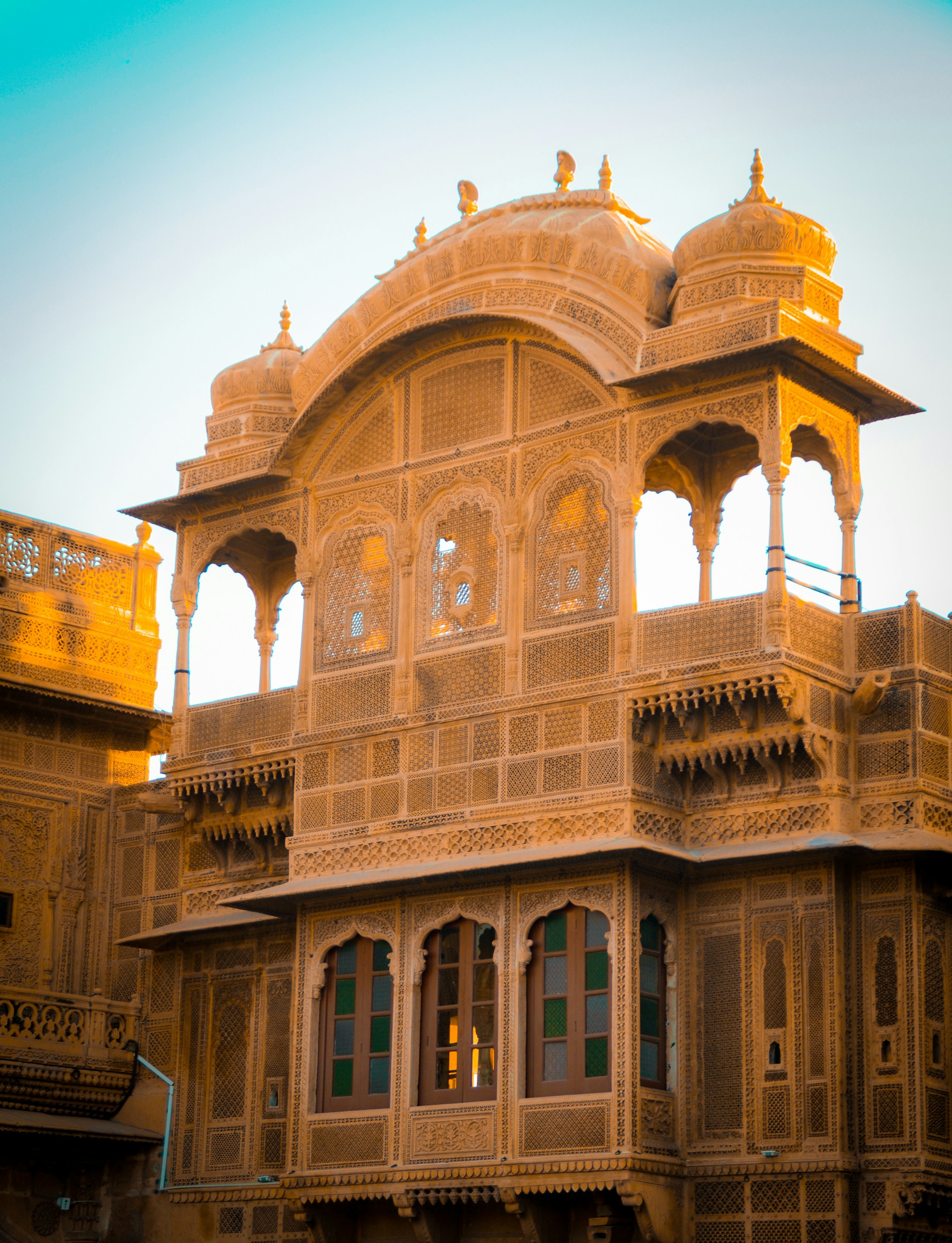 A historic Mughal-era palace with intricate carvings and arches bathed in warm sunlight.