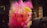 A bunch of cotton candy packaged in transparent plastic bags, displaying vibrant colors in pink and yellow hues. The background is slightly blurred, highlighting the bright candy against darker surroundings.