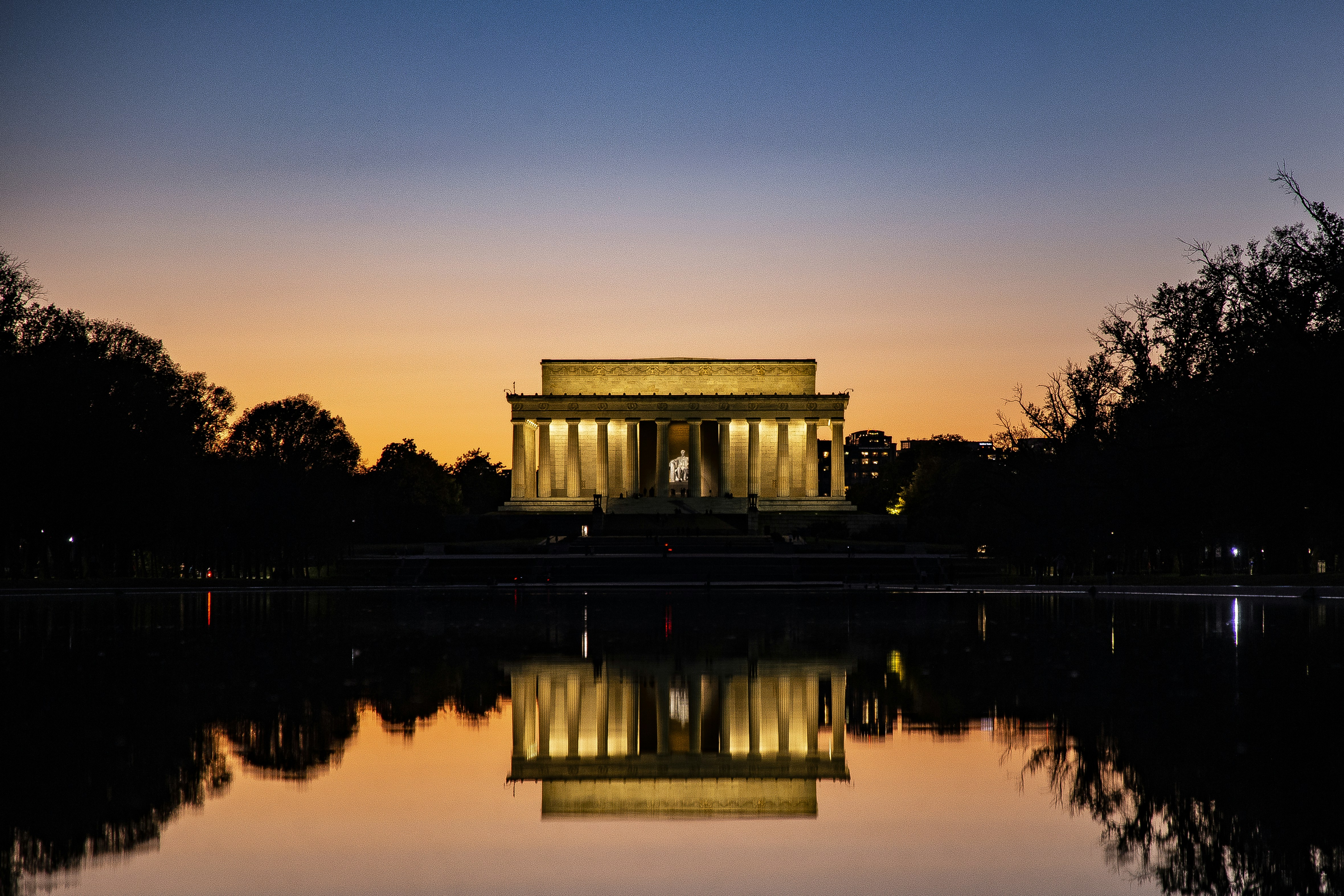 body of water near trees during sunset