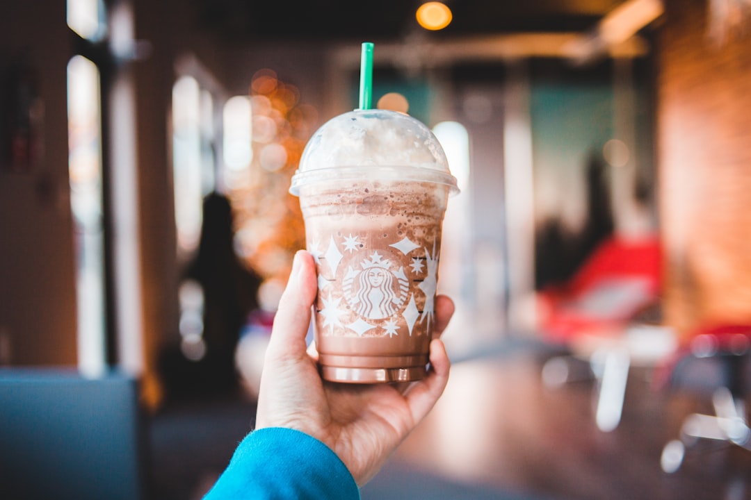 person holding white and brown starbucks cup