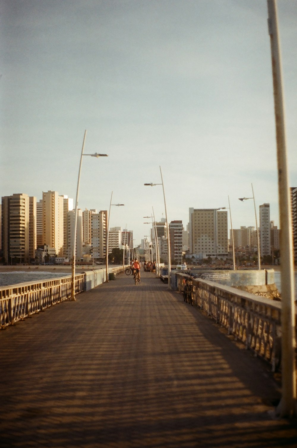 people walking on gray concrete bridge near city buildings during daytime