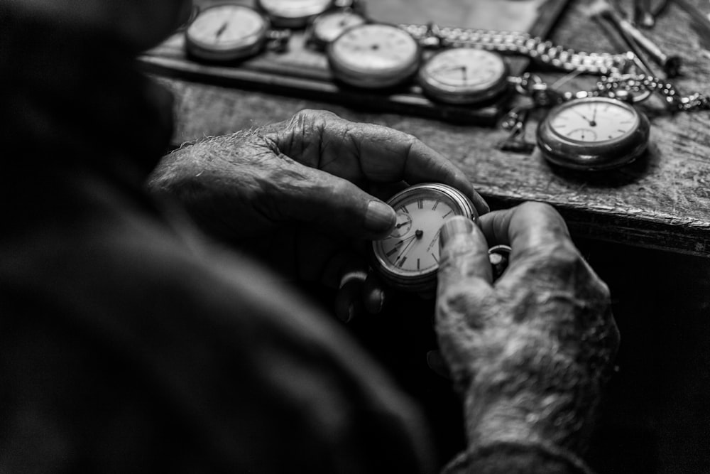 Foto en escala de grises de una persona sosteniendo un reloj de bolsillo