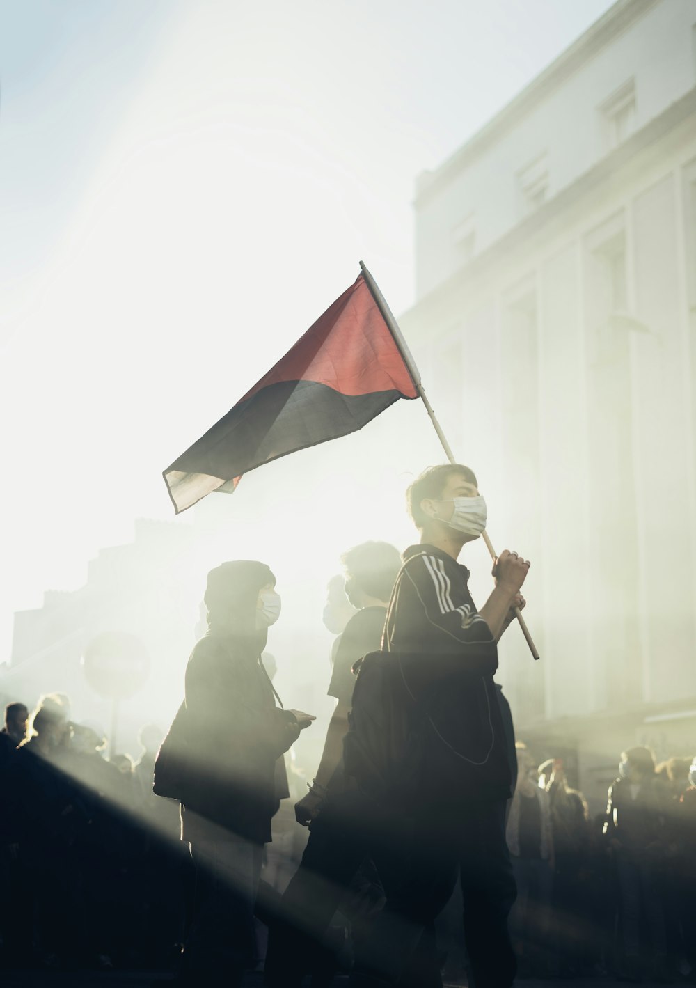 woman in black long sleeve dress holding black and red flag