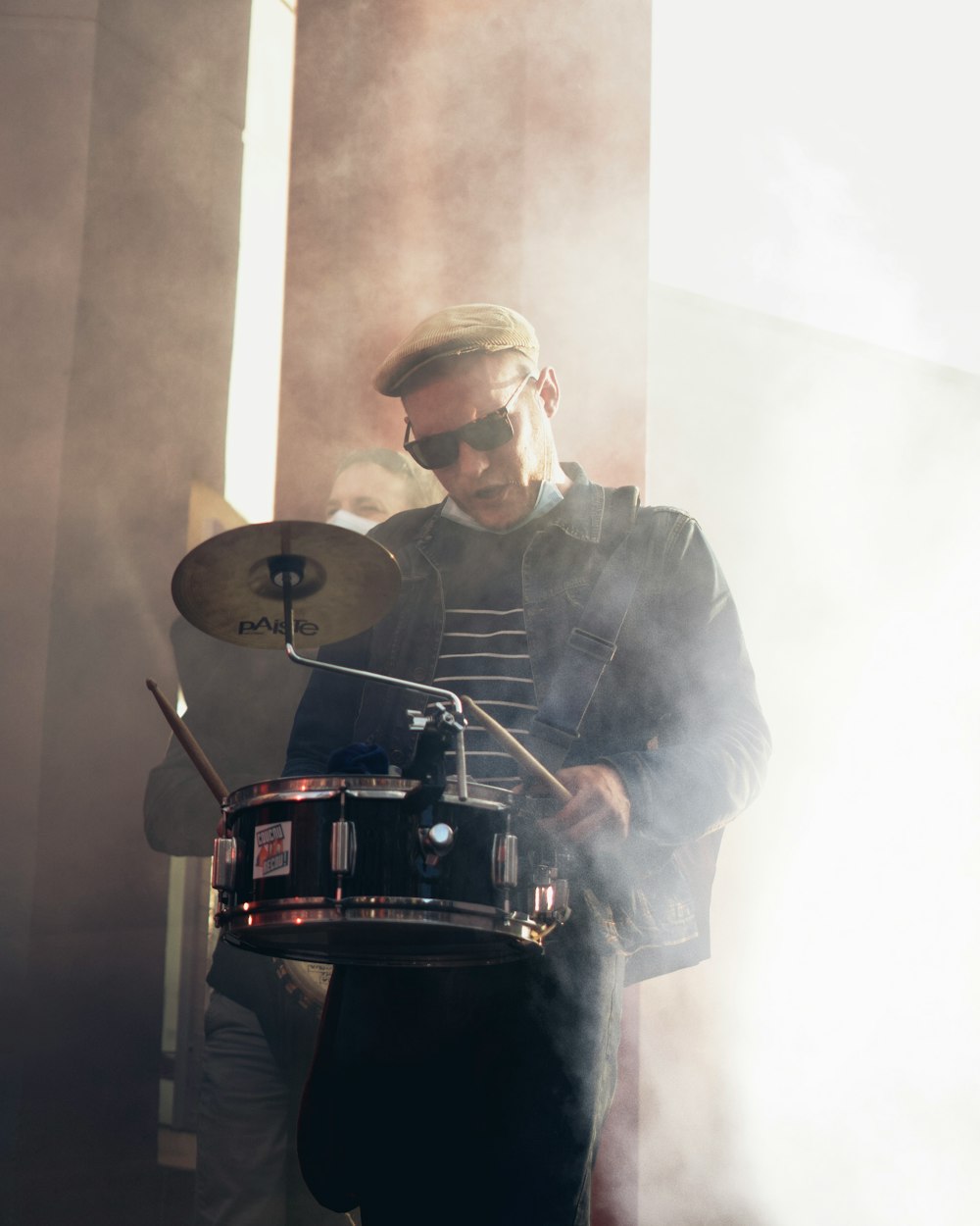 man in black jacket and black cap playing drum