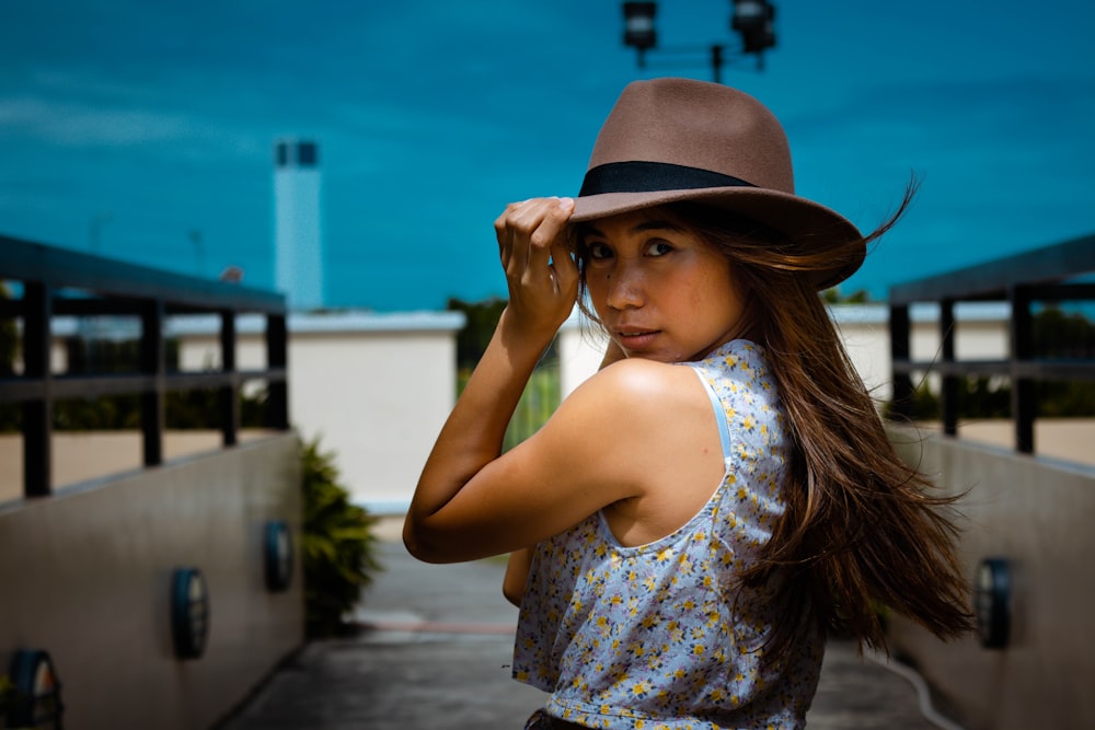 woman in white and blue floral tank top wearing brown fedora hat