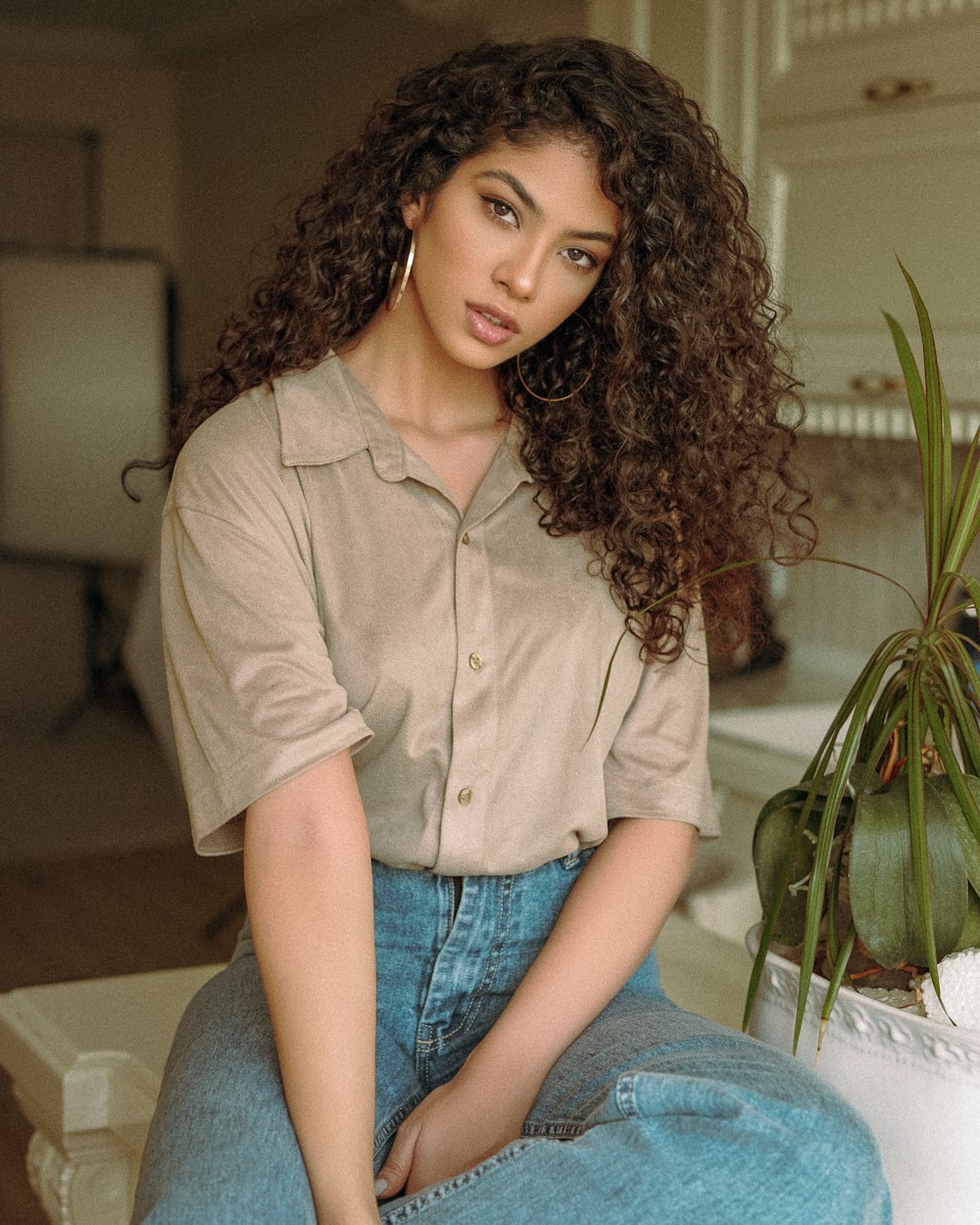 mulher no botão marrom até camisa e jeans azul sentado no sofá branco