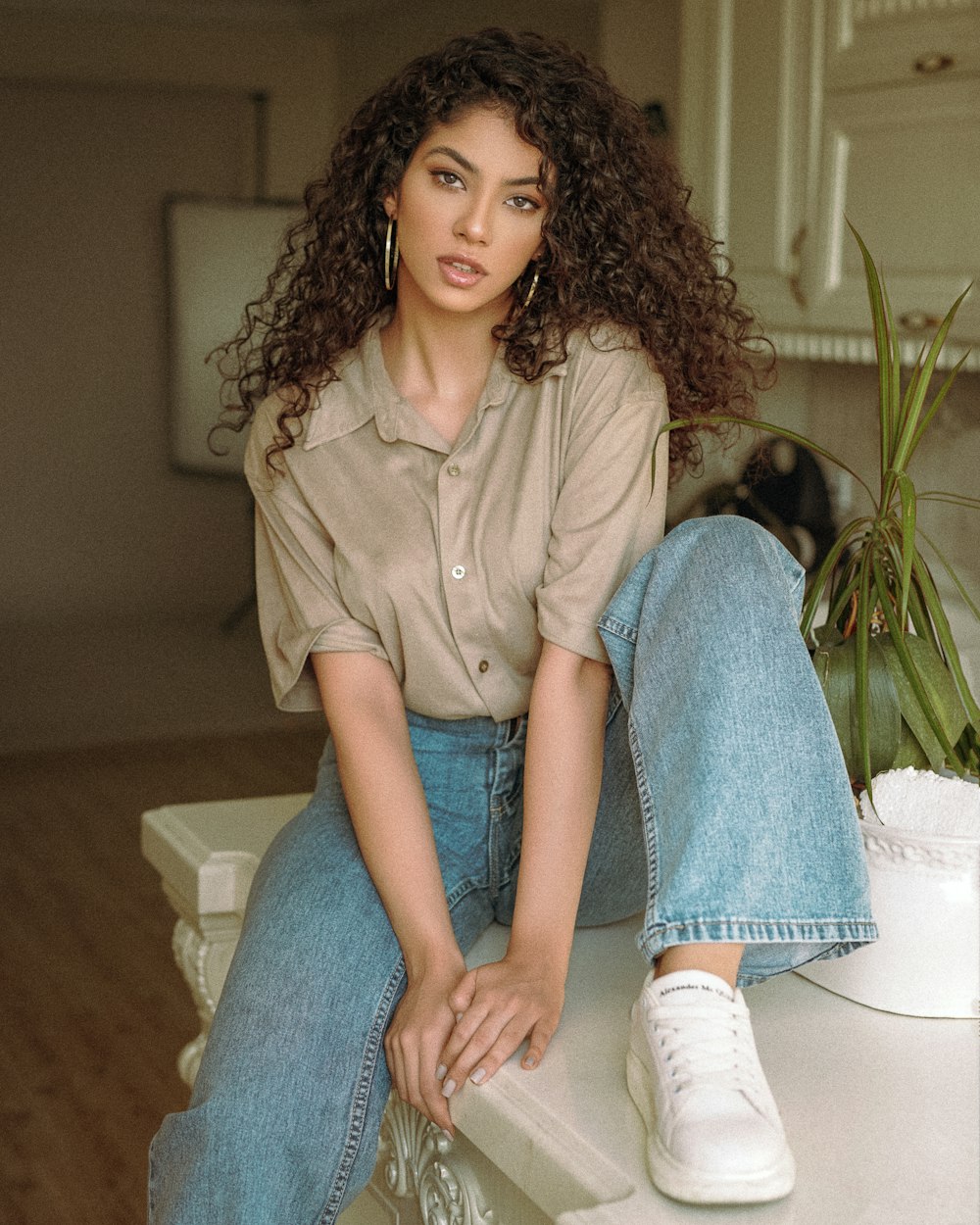 woman in brown button up shirt and blue denim jeans sitting on white couch