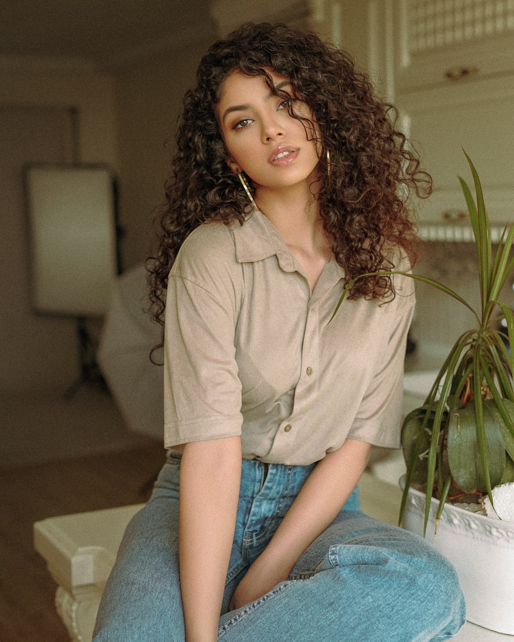 woman in brown button up shirt and blue denim jeans sitting on white couch