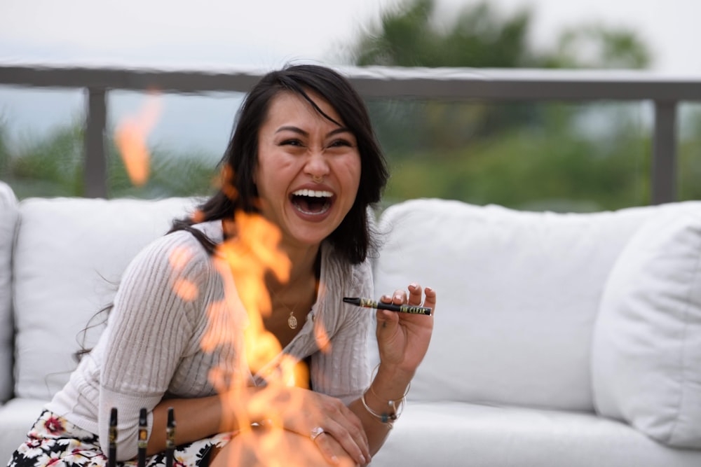 Mujer sonriente en camisa a rayas blancas y negras sosteniendo bengala encendida durante el día