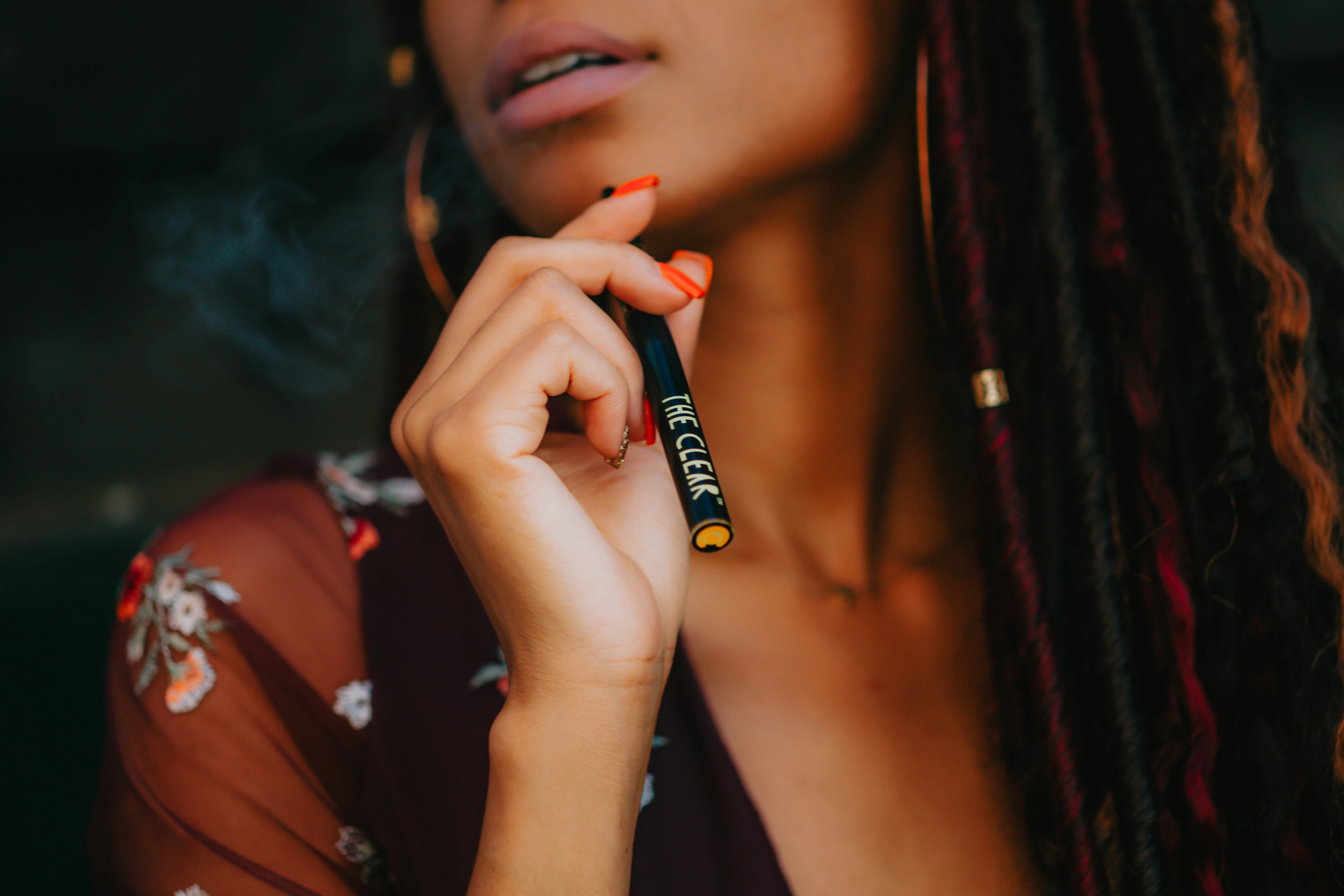Close up of woman with manicured hand holding the clear vape pen. The clear makes vape pens for every kind of cannabis consumer over 21 in Colorado.