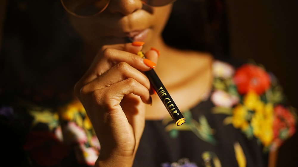 woman holding black and orange pen