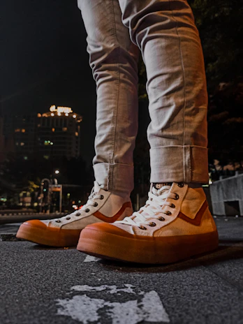 Customer wearing vibrant sneakers, casually leaning against a dark urban wall at night.