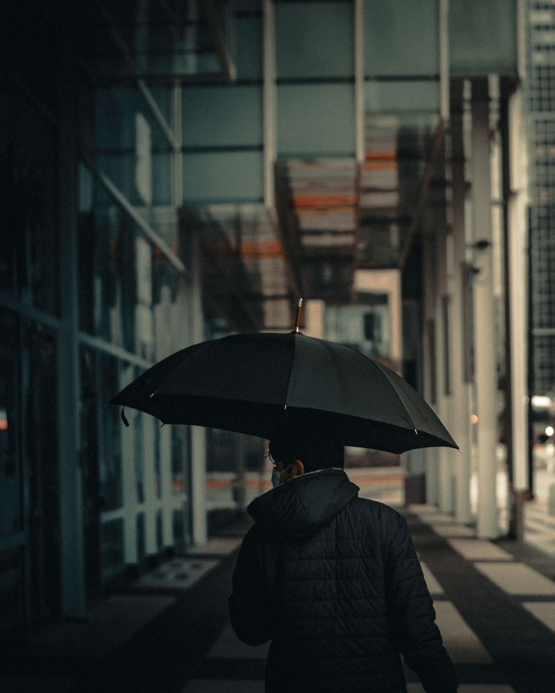 person in black coat holding umbrella walking on sidewalk during night time