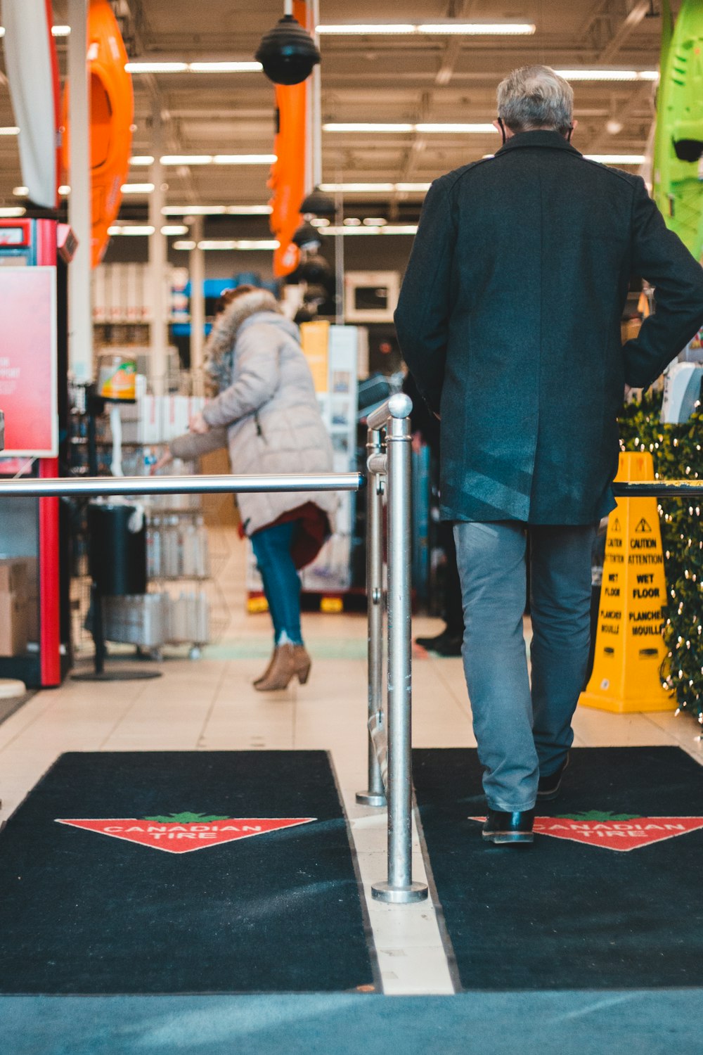 homme en veste noire debout à côté d’un poteau en acier inoxydable