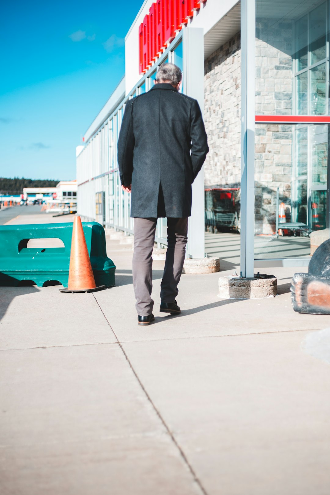 man in black suit standing on sidewalk during daytime