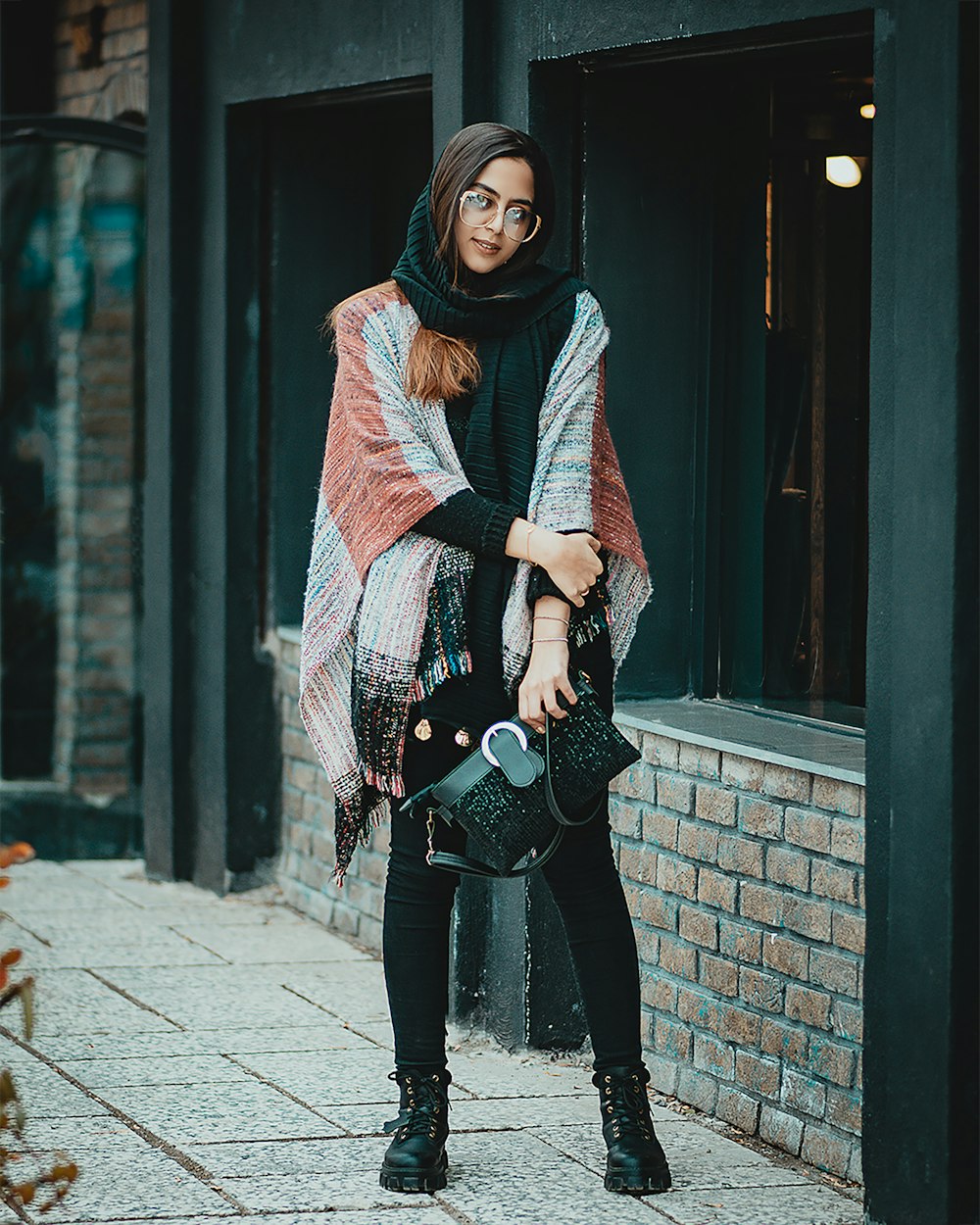 woman in black pants and red scarf standing on sidewalk during daytime