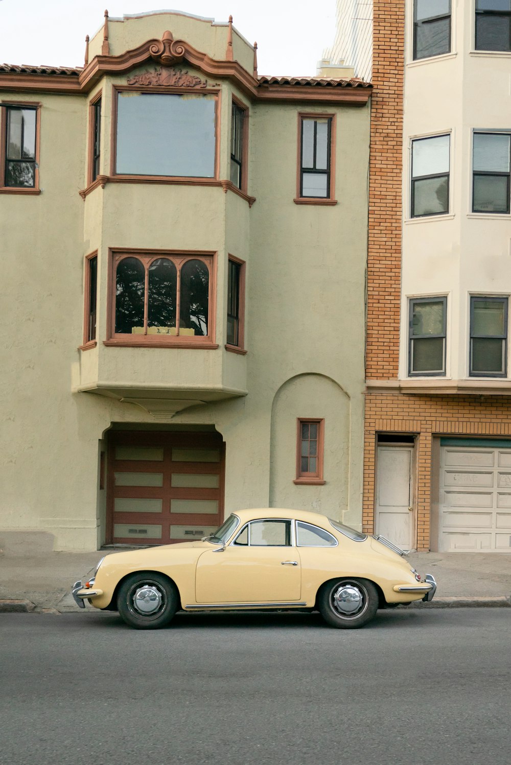 yellow coupe parked beside brown concrete building during daytime