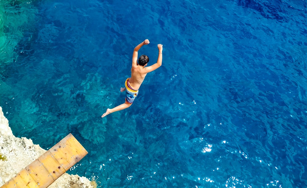 昼間、水の上を飛び跳ねる青い半ズボンの男