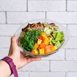 person holding vegetable salad in clear glass bowl