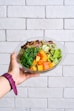 person holding vegetable salad in clear glass bowl